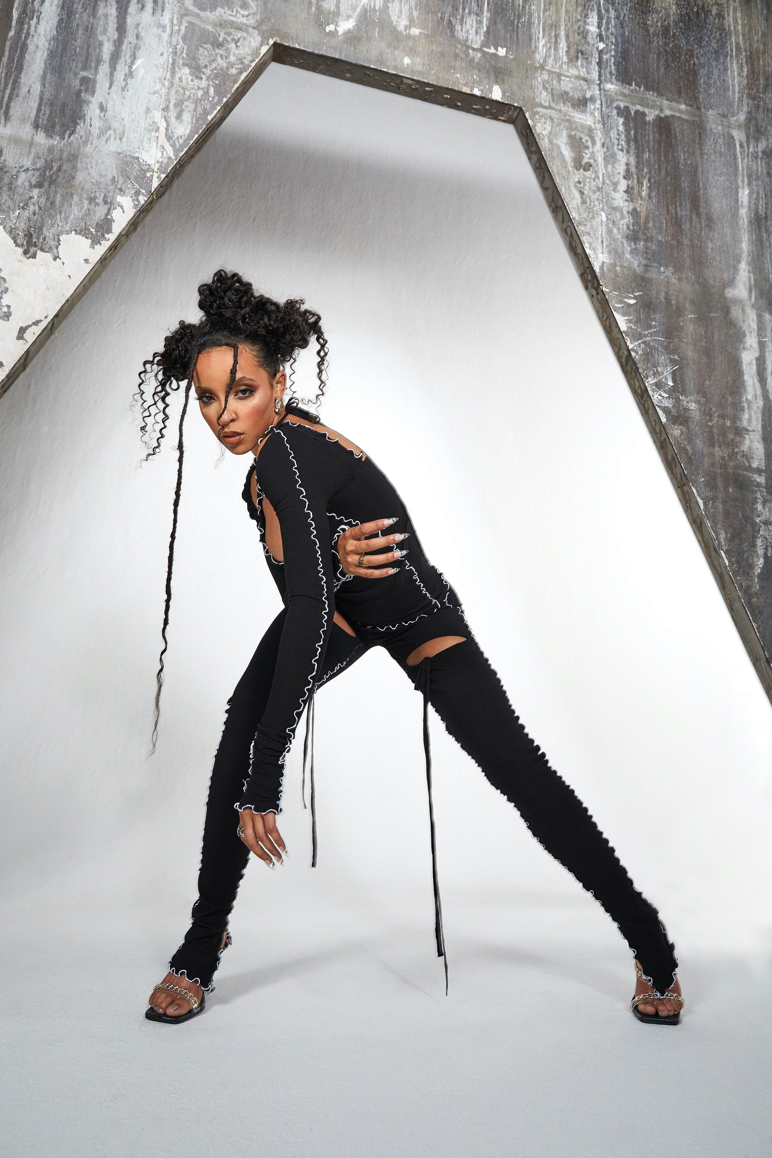 Tinashe poses in all-black against a white wall 